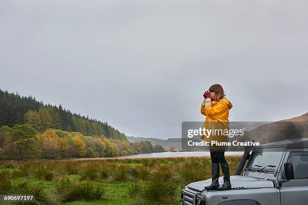 woman standing on car taking photo - women in see through tops stock pictures, royalty-free photos & images