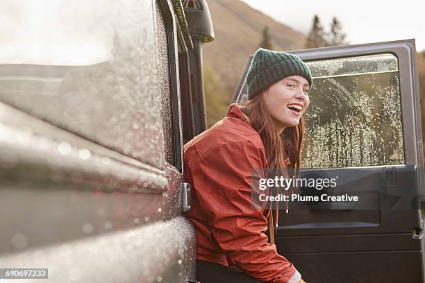 portrait of young woman peering out of car - car rain stock pictures, royalty-free photos & images