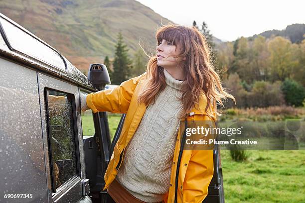 woman leaning out of car looking at landscape - raincoat stockfoto's en -beelden