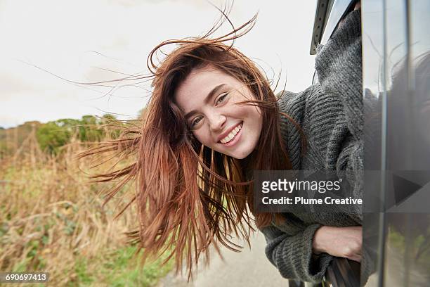 young woman with head out of car window - tossing hair facing camera woman outdoors stock pictures, royalty-free photos & images