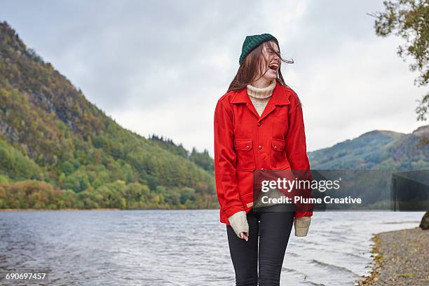 woman standing by the side of a loch - red jacket stock pictures, royalty-free photos & images