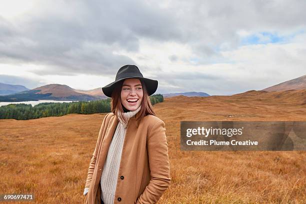 woman laughing in autumnal landscape - scottish coat stock pictures, royalty-free photos & images