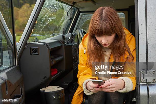 young woman with smartphone in car - wellington boots stock pictures, royalty-free photos & images