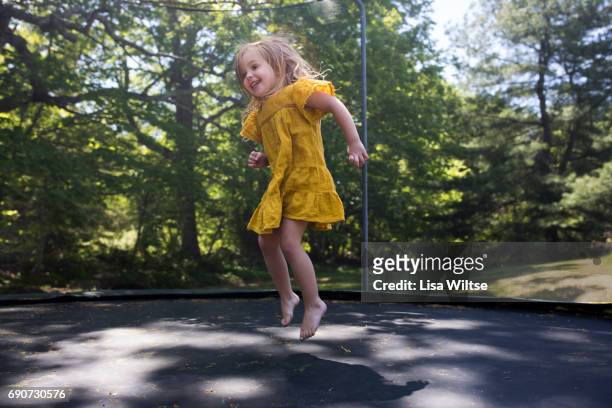 young girl on trampoline - girl in yellow dress stock pictures, royalty-free photos & images
