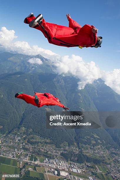 wingsuit fliers glide above mountain landscape - wing suit stock pictures, royalty-free photos & images