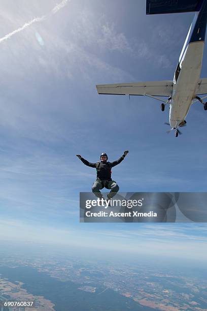 sky diver in free fall below plane, above lake - base jumping stock pictures, royalty-free photos & images