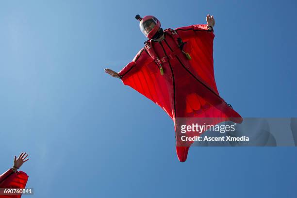 wingsuit fliers endeavour to clasp hands - tomber en chute libre photos et images de collection
