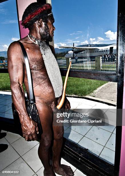 dani man wearing kotekas (penis gourd-sheath) in the airport waiting the the departure of his flight, baliem valley, western new guinea, indonesia. - koteka stock pictures, royalty-free photos & images