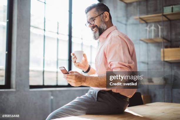 kleine pauze met mijn telefoon - male looking content stockfoto's en -beelden