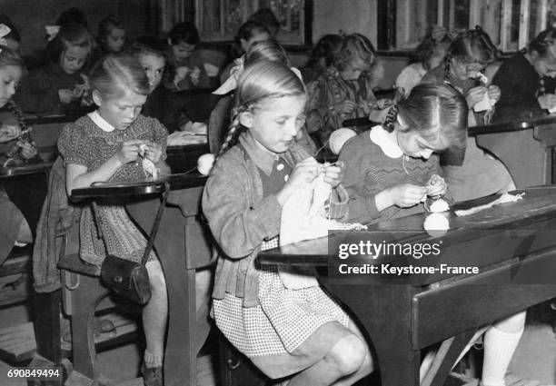 Petites filles allemandes tricotant des chaussettes pour leurs frères et soeurs cadets, dans une école située dans la zone d'occupation américaine à...