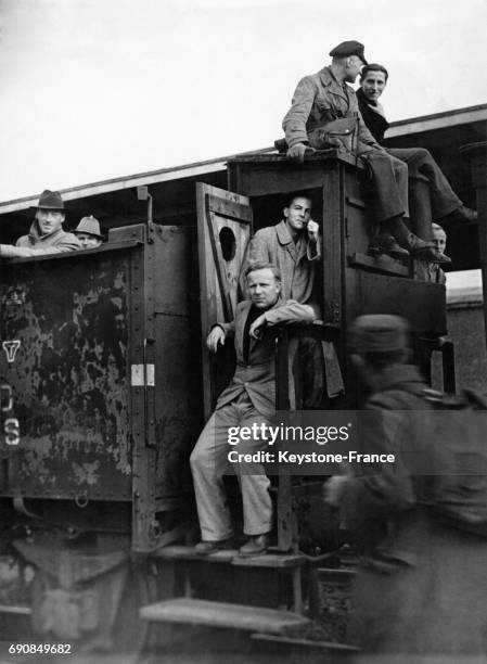 Des hommes assis sur la locomotive tirant des wagons à bestiaux utilisée comme moyen de locomotion, en Allemagne en 1945.