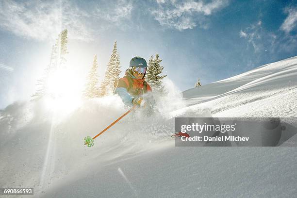 skier takig a turn in deep powder on a sunny day. - pista de esquí fotografías e imágenes de stock