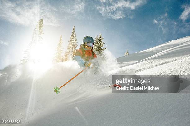 skier takig a turn in deep powder on a sunny day. - colorado skiing stock pictures, royalty-free photos & images