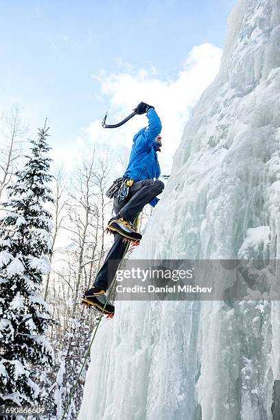 climber using ice axe to climb a frozen waterfall. - frozen waterfall stock pictures, royalty-free photos & images