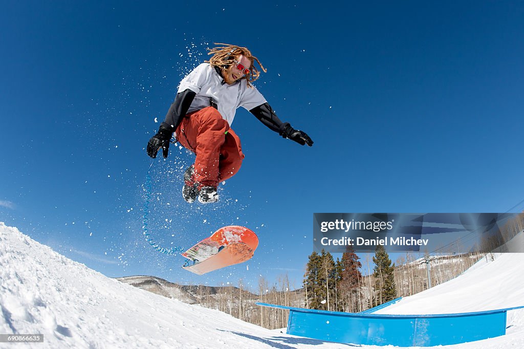Goy with dreadlocks doing tricks on a snowskate.