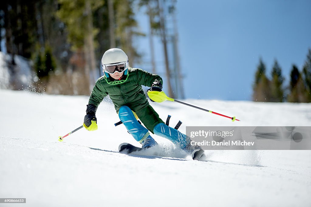 Young kid racing skis on a sunny day.