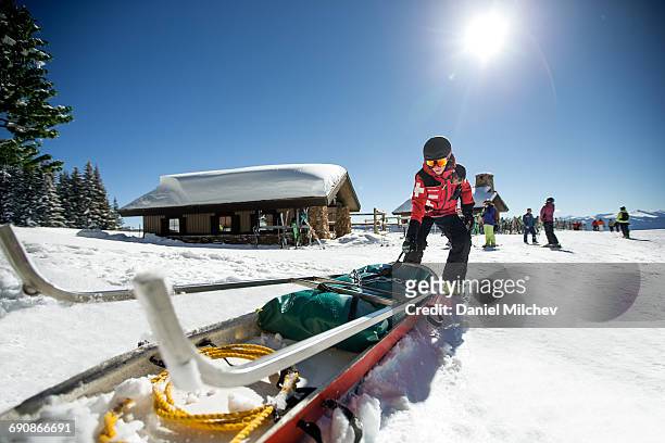 female ski patrol pulling medical sled. - ski patrol stock-fotos und bilder