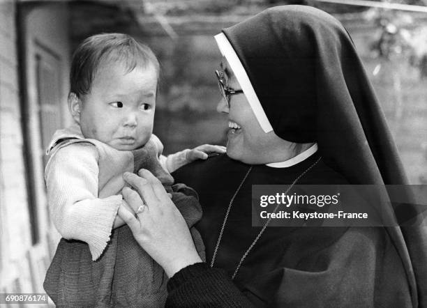 Bébé dans les bras d'une bonne soeur en Corée le 17 décembre 1969.