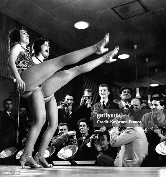 Deux danseuses de cabaret sur la scène devant un public de photographes enthousiasmés.