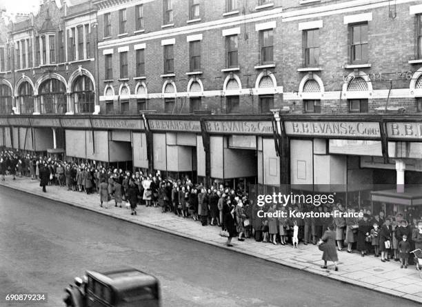 Vue de l'immense file d'attente devant un magasin sur Kilburn High Street qui solde les bas nylons, à Londres, Royaume-Uni le 4 janvier 1947.