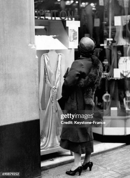 Jeune femme devant une cabine d'essayage installée dans la rue, à Londres, Royaume-Uni le 21 mai 1935.