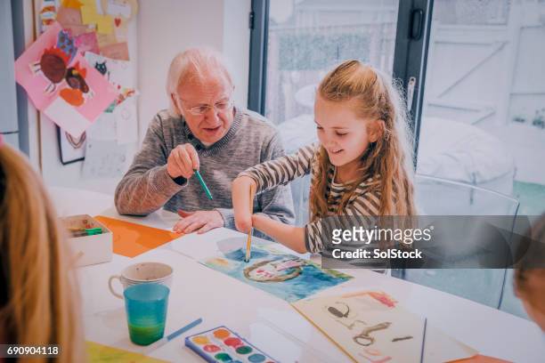 meningitis survivor painting on the dining room table with grandpa! - western europe stock pictures, royalty-free photos & images
