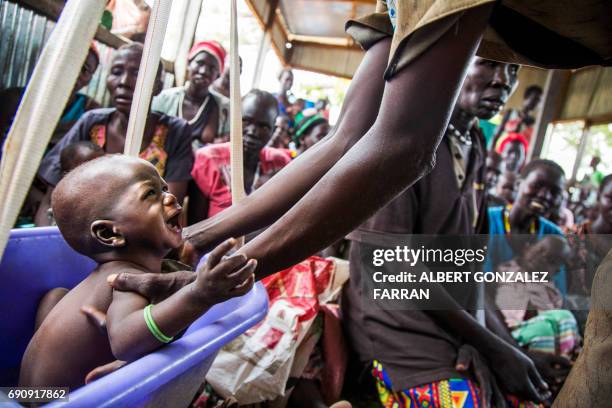 Mother weights her malnourished child on May 31 in a nutrition centre run by the International Rescue Committee in Panthau, Northern Bahr al Ghazal,...
