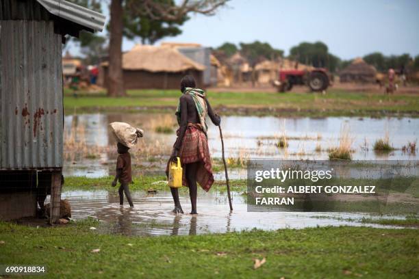 Woman with a boy walk in a flooded area on May 31 in Panthau, Northern Bahr al Ghazal, South Sudan. The rain is a threat for many farmers in the...