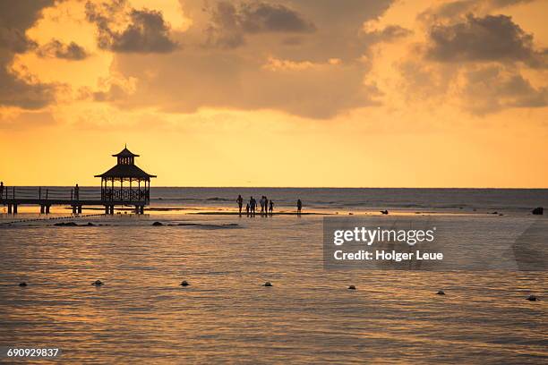 silhouette of people and jetty pavillion at sunset - montego bay stock pictures, royalty-free photos & images