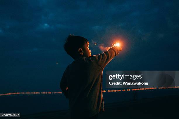 a boy playing with fireworks - bengala fuego artificial fotografías e imágenes de stock