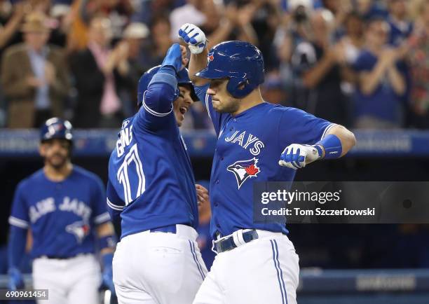 Luke Maile of the Toronto Blue Jays is congratulated by Ryan Goins after hitting a two-run home run in the fifth inning during MLB game action...