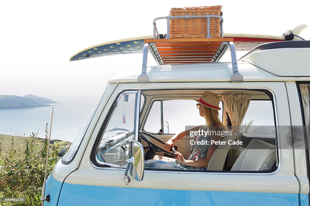 Woman sat in camper on coastal road