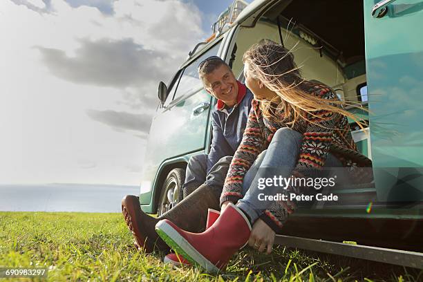 couple putting on wellies sat in door of camper - adventure couple stock pictures, royalty-free photos & images