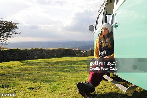 woman in door of camper on moors reading a book - book sleeve stock pictures, royalty-free photos & images