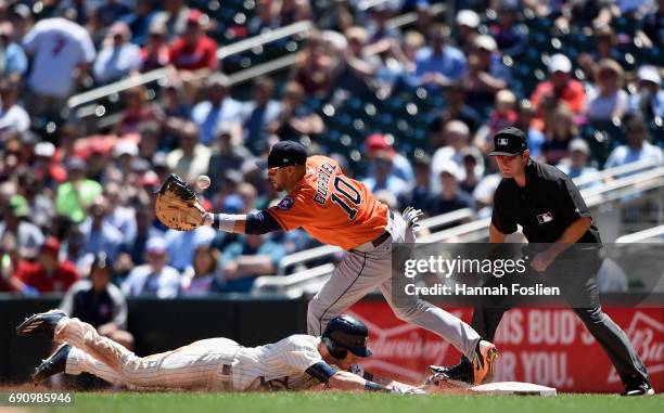 Max Kepler of the Minnesota Twins dives safely back to first base as Yuli Gurriel of the Houston Astros is unable to field the ball and umpire Ben...