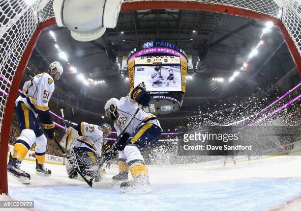 Mike Fisher of the Nashville Predators sprays ice as he helps defend the net with teammates Austin Watson and goaltender Pekka Rinne during the first...