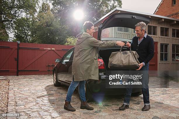 happy woman giving bag to man by car on driveway - brandenburg gate bildbanksfoton och bilder