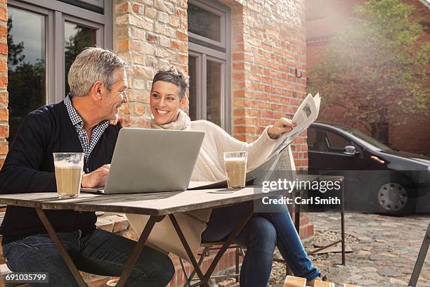 happy mature couple reading newspaper with laptop in back yard - man in car reading newspaper stock pictures, royalty-free photos & images