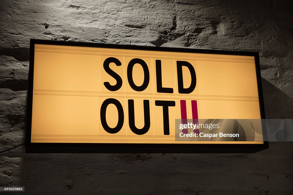 Close-up of Sold Out signboard against gray wall