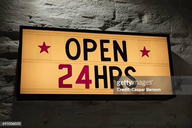 close-up of open 24 hours signboard against gray wall - 24 hours stock pictures, royalty-free photos & images