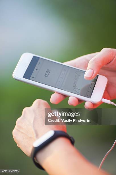 cropped image of woman using pedometer and mobile phone - podomètre photos et images de collection