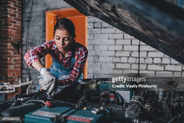 female mechanic repairing car engine at garage - auto mechanic stock-fotos und bilder