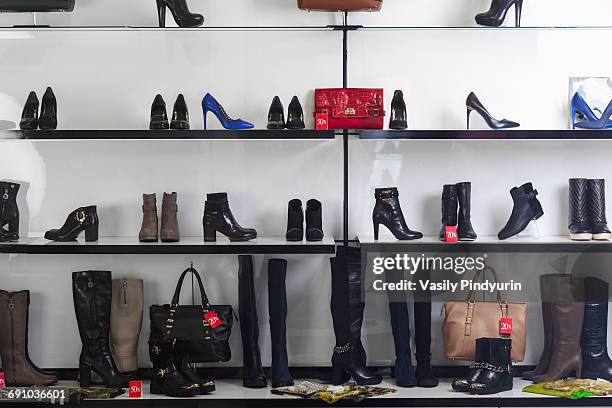 various shoes and purses displayed on shelves at store - schoenenwinkel stockfoto's en -beelden