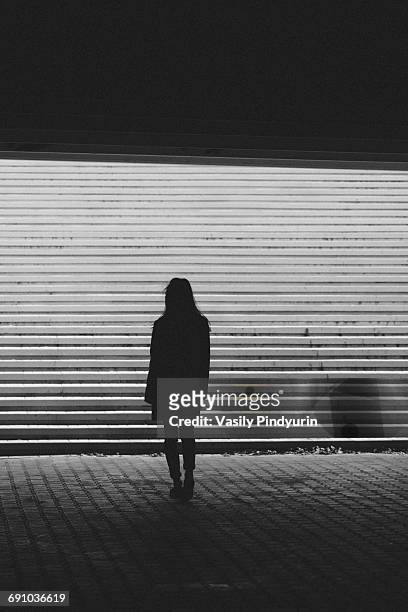 silhouette woman standing by steps on sunny day - standing female rear view stock-fotos und bilder