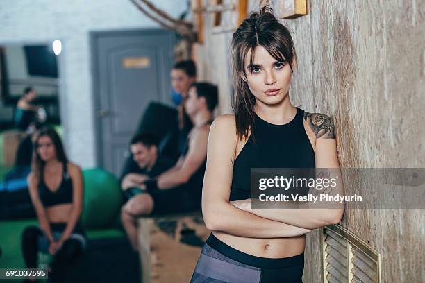 portrait of confident female athlete standing arms crossed with friends in background at health club - bangs bildbanksfoton och bilder