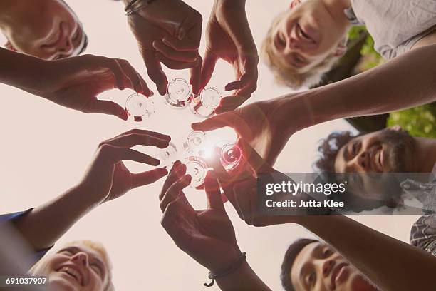directly below shot of friends toasting tequila shots against sky during summer - spirituosen stock-fotos und bilder