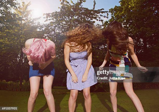 excited female friends tossing hair at yard during sunny day - party girls stock-fotos und bilder