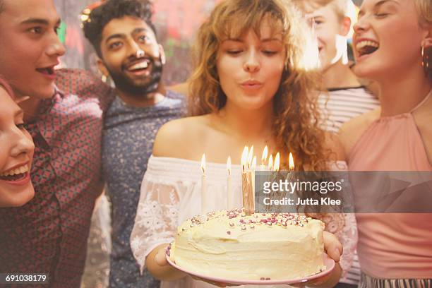 woman blowing candles while celebrating birthday with friends - teen birthday stock-fotos und bilder