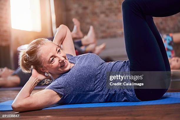 Mature woman doing sit-ups in exercise class gym studio