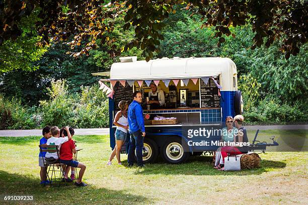 people around a blue mobile coffee shop on a lawn. - horse trailer stock pictures, royalty-free photos & images
